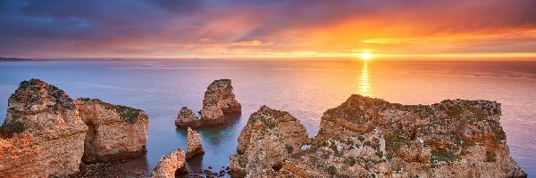 Wschód słońca, Cypel Ponta da Piedade, Morze, Region Algarve, Portugalia, Chmury, Skały